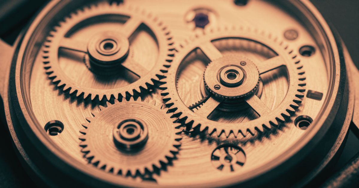 The exposed movement of a mechanical watch, gears and mainspring meshed mid-motion