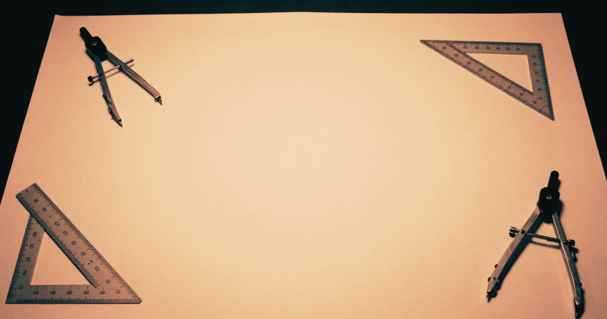 An architect's drawing table seen from above, precision tools arranged at the edges, clean empty surface in the centre