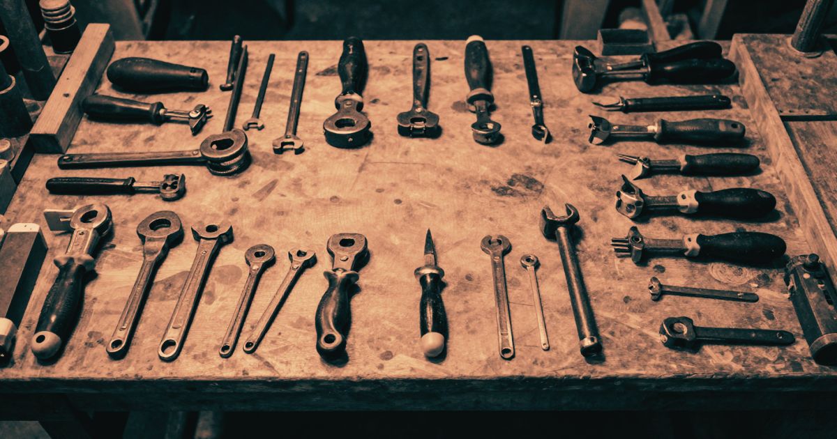 A craftsman's workbench covered in an excessive number of different hand tools, all laid out but none in use