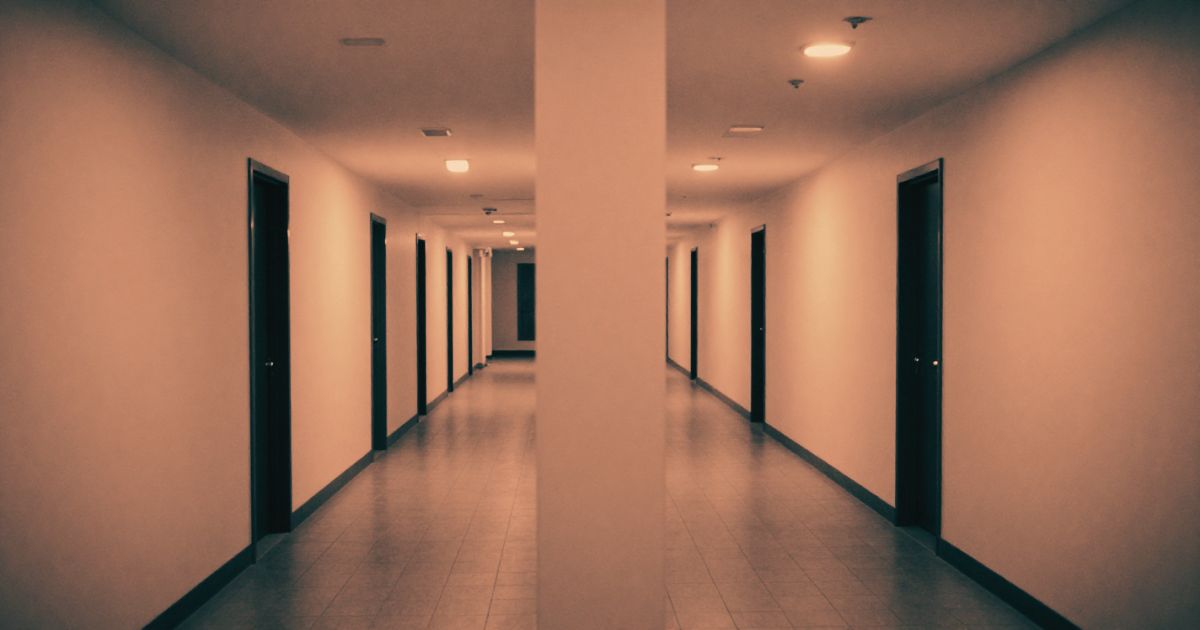 A long corridor splitting into two identical-looking passages, shot from the junction point