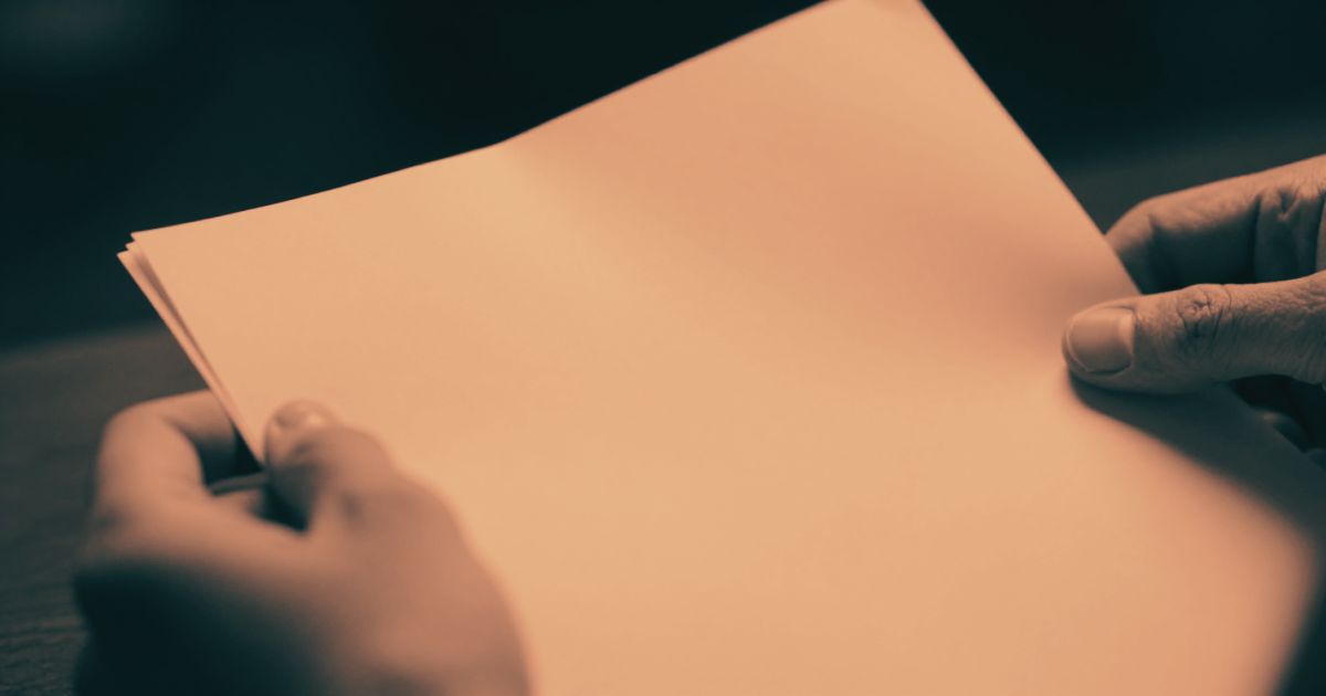 Hands holding a printed document, one hand about to turn the page